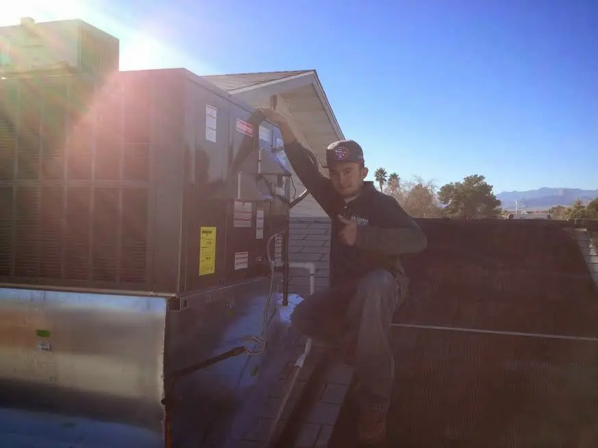 HVAC technician performing Heat Pump Repair on a rooftop unit in Tuttle